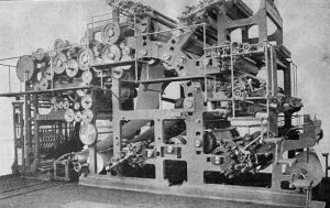 A black and white image of a big machine with many wheels and rollers, a modern invention from the industrial revolution