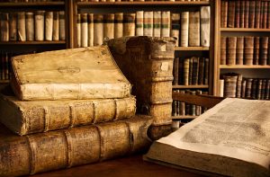 Three ancient translation books are stacked, one is standing and another lies open on a table in a library, history preserved