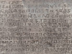 A grey stone carved with ancient Buddhist script fills the frame. Buddhist monks made a huge contribution to the history of translation