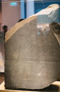 A partly damaged stone tablet shows three distinct sections of inscribed writing, translated into three different languages. The most famous discovery in translation history